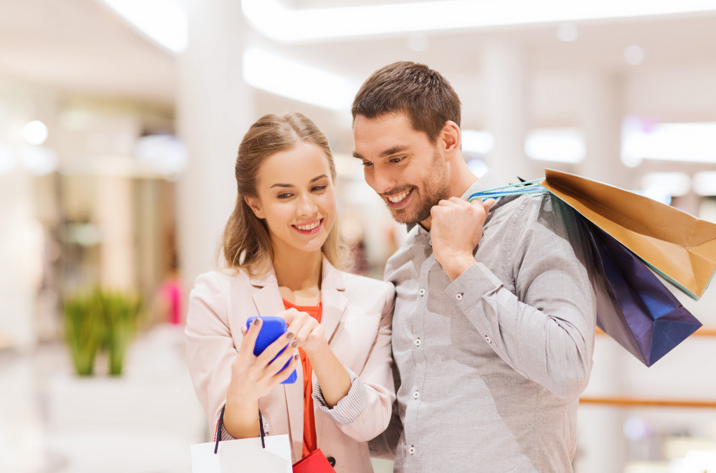 customers with shopping bags looking at phone