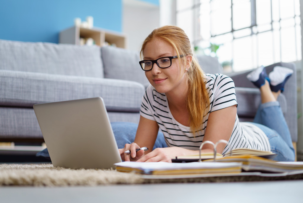 woman laying down on the floor working on laptop