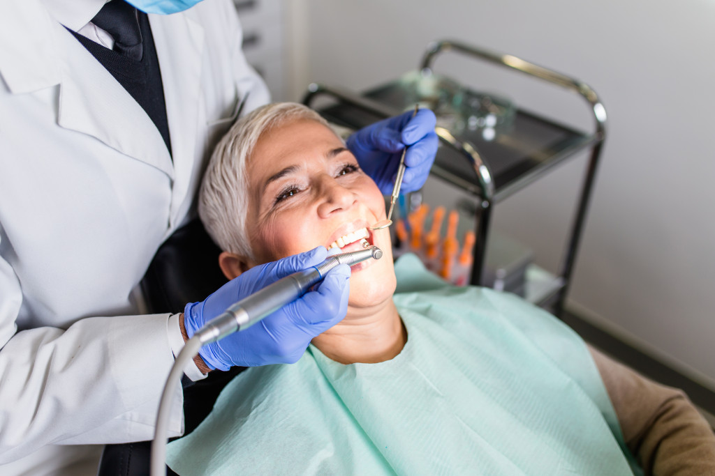 mature white woman's teeth is being checked upon by a doctor