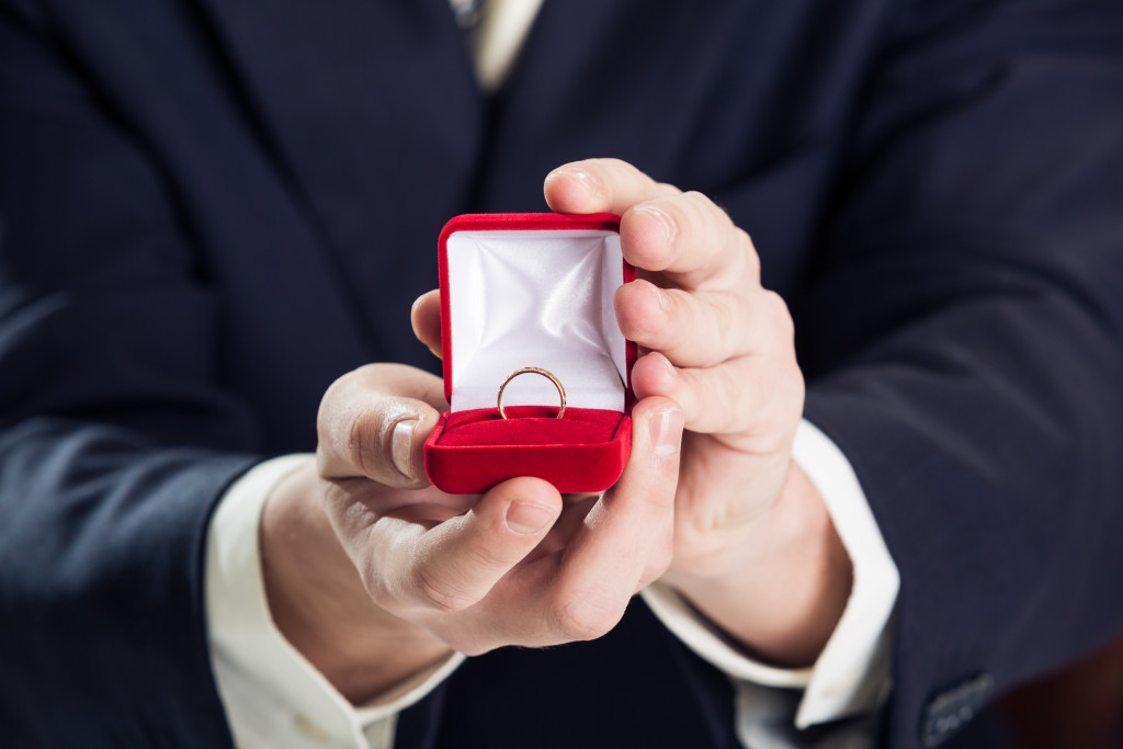 Close up of a man holding a gift box with a wedding ring.