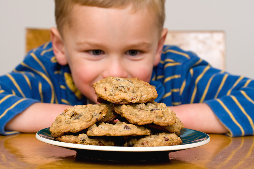 A kid staring at a plate of cookies