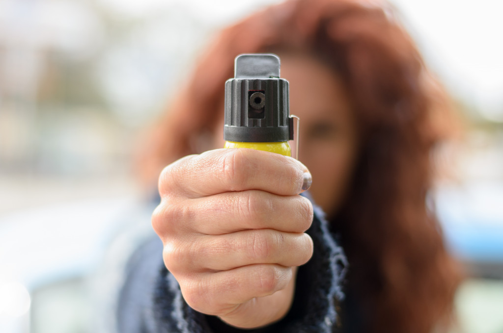 A woman holding up a bottle of pepper spray