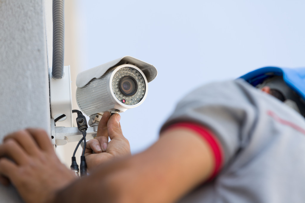 A CCTV camera is being installed by a technician onto a wall