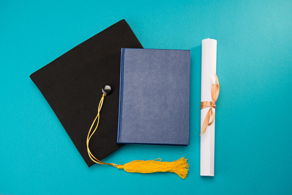 graduation cap and diploma against light blue background