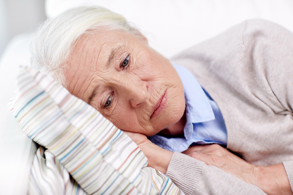 A sad senior lady laying on her bed