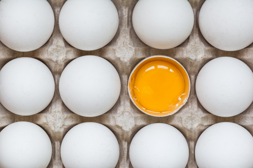 A tray of eggs with one open one showing the yolk