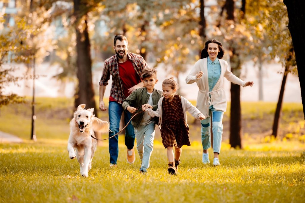 happy family running at the park with their pet