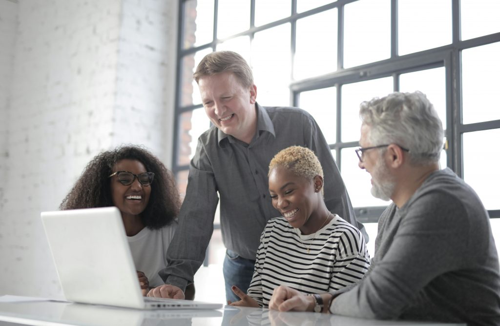 group of 4 people huddled around a laptop
